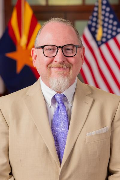 Jason O'Leary posing in front of alternating American and Arizonan flags.